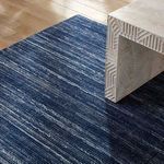 Close angled view of rug under edge of textured white console on wood floor