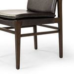 Detailed view of black leather seat cushion and surrounding burnt oak frame corner