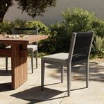 Sherwood Grey chair arranged at outdoor wooden dining table with lush green garden backdrop