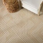 Detailed aerial view of chevron rug pattern beneath white armchair and wicker accent table