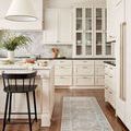 narrow runner rug placed in bright kitchen with white cabinetry and dark counter seating