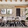 Langham sectional styled in a rustic room with stone wall, black striped rug, and a green armchair