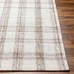 Close-up of rug edge on wood floor showing fine woven details and natural fibers