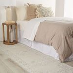 Gray and white runner rug paired with neutral bedding and wood nightstand in bedroom