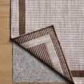 Corner of Easton Dove Coffee rug flipped up to reveal underside and floor pad underneath