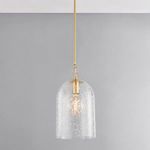 Pendant lit with warm light casting subtle shadows in etched glass against grey wall