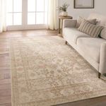 Rug laid out in bright living room with sofa and light wood flooring highlighting its soft gold pattern