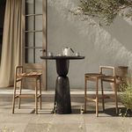Table shown in outdoor patio setting with two wooden bar stools and natural sunlight