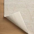 Kamala rug corner lifted to show woven natural fiber backing and tightly hemmed edges