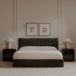 Gallery setting with two framed prints above dark green tufted bed and bedside lamps in bedroom