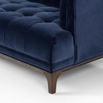 Close-up detail of navy velvet tufted seat cushion and tapered wood leg