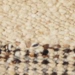 Extreme close-up showing chunky wool weave with cream, brown, and black fibers