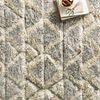 Close-up of thick textured wool fibers highlighting plush shaggy surface and intricate hand-knotted diamond motifs