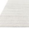 Close-up angled view showing low pile texture and subtle striped pattern of the ivory rug edge