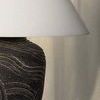 Close-up view of off-white linen shade and ceramic base detail with soft shadows from draped fabric