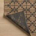 Folded corner of Judy Natural / Graphite Rug flipped to show dark gray backing with grid pattern