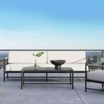 Pietra Sofa in light neutral cushions shown outdoors with matching low coffee table and city skyline backdrop