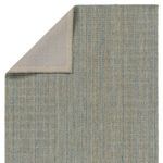 Rug corner flipped to reveal solid cream fabric backing with stitched border