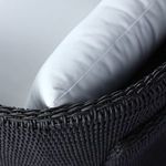 Sharp side stitch detail on white olefin back pillow against black wicker frame