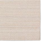 Close-up detail of diamond trellis pattern with tan accents on cream background on rug corner