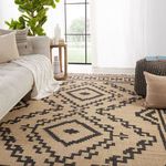 Jaima rug styled in a bright living room with couch, side table, pillows, knit pouf, and large window