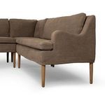 Close-up of rounded sloping arm and textured linen upholstery with wooden tapered leg detail.