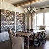 Dining room setting with the chair at table corner under chandelier and next to patterned wall art