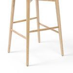 Close-up of front tapered legs and footrest connecting the stool’s slender frame