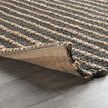 Corner of rug lifted to show natural fabric backing and underside stitching