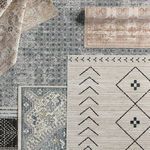 Top view of cream and dark slate tribal rug surrounded by various patterned and colored rugs rolled and displayed