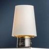 Angled view focused on the lamp’s top brass carriage securing the white linen shade