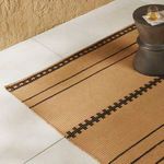 Vallarta Brown outdoor rug laid on light tile floor next to textured tan wall with small dark side table on rug