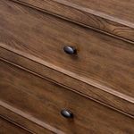 Close-up on two dark gunmetal oval drawer pulls with visible wood grain texture