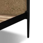 Close-up detail of tapered black iron leg supporting the bed frame at the footboard corner