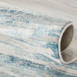 Rug rolled to highlight plush viscose fibers and color variation in blue, ivory, and gray hues