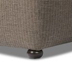 Close-up view of dark rounded wooden bun feet on Kylo Ottoman with fabric folds above