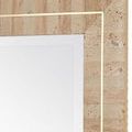 Close-up of travertine tile texture and polished brass inlay on mirror frame corner