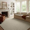 Polly Spa rug laid flat in a bright living room with sofa, fireplace, and leather armchair