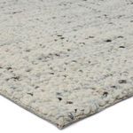 Close-up corner showing chunky woven wool fibers with cream and gray flecks and textured edge