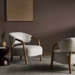 Close-up showing front corner oak leg and ivory upholstery contours from side angle