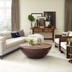 Coffee table in bright airy living room with white sectional, wooden framed chairs, and console table with framed art