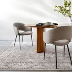Davina rug styled under round wood dining table with gray upholstered chairs in bright room