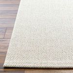 Detailed close-up of Birdie Light Beige rug’s finished edge and dense weave on hardwood floor