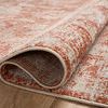 Rolled edge of rug revealing soft polyester material and backing on wood floor