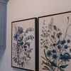 Side view of two framed paintings hung side by side on white wall including Blue Meadow Reverie I.
