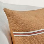 Close-up of pillow on a white fabric surface emphasizing woven texture and striped tape