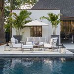 Roma Lounge Chair styled on outdoor patio poolside with matching sofas, ottoman, umbrella, and tropical plants