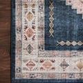 Close-up corner of rug on dark wood floor highlighting faded blush and denim blue pattern details