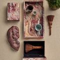 Overhead view of opened boxes with small ceramic items inside and a brush resting on the fabric surface