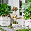 Two gold hammered balls styled on a glass and gold metal outdoor table with greenery